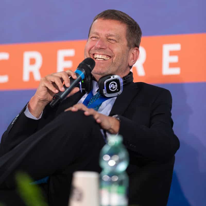 Audio per Conferenze Lächelnder Redner mit Mikrofon und Kopfhörern auf einer Konferenz