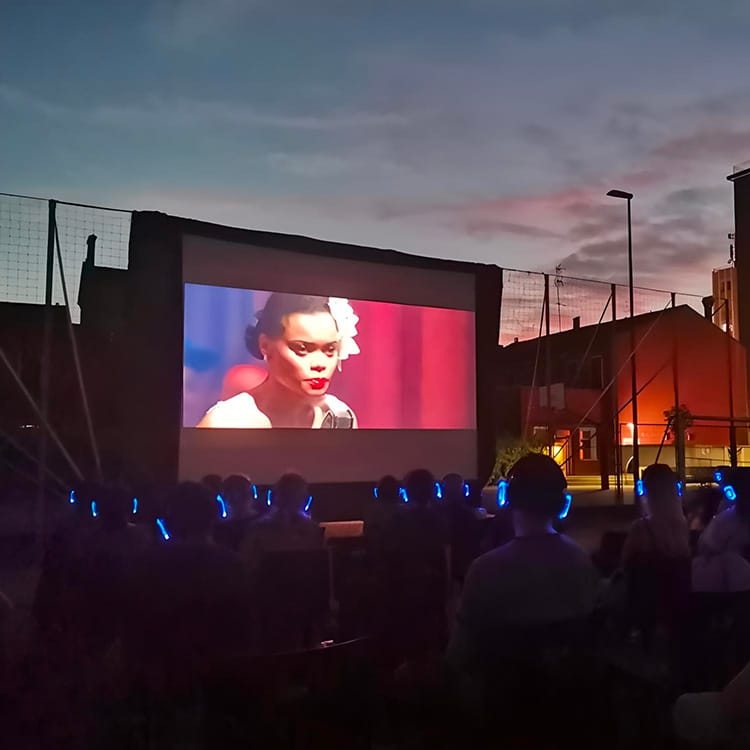 cinema-bologna Open-Air-Kino in Bologna bei Sonnenuntergang, Publikum mit Kopfhörern