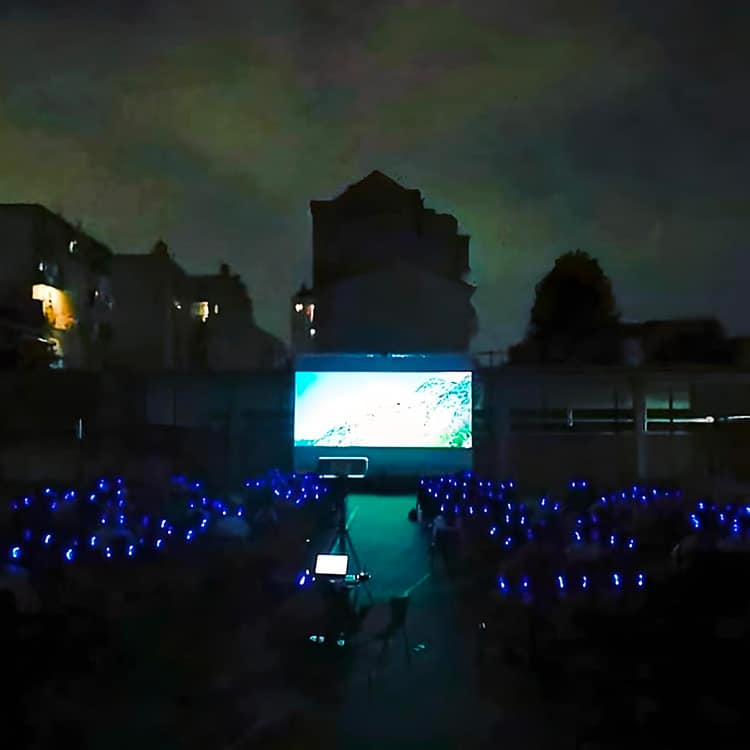cinema-cuffie-milano Open-Air-Kino in Mailand bei Nacht mit Kopfhörern mit blauen LEDs