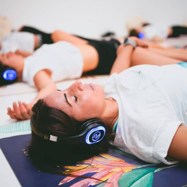 inspirafit Liegende Frauen mit kabellosen Kopfhörern bei einer Silent-Fitness-Stunde